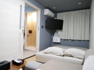 Un dormitorio con una cama y un televisor en la pared. en HOOD - Vacation STAY 19649v, en Amami