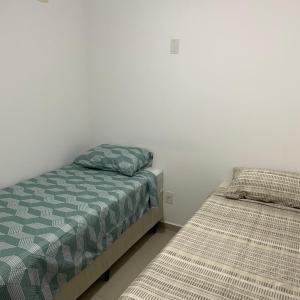 two beds in a room with white walls at Descanso e lazer in Parnamirim +5 photos