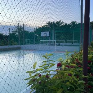 a fence with a basketball hoop on a tennis court at Descanso e lazer in Parnamirim
