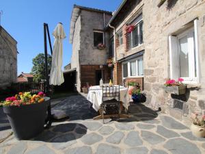 a table and an umbrella in front of a building at Maison familiale près du Parc Régional du Pilat - FR-1-582-49 in Saint-Just-Malmont