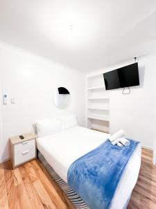a white bedroom with a bed and a tv at big group entire house 15 beds in Sleeps Hill Station