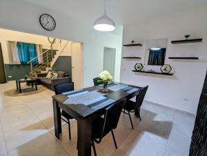 a dining room table with chairs and a clock on the wall at Cozy Modern 2BR Rooftop Terrace by ATW Accommodations in Oranjestad