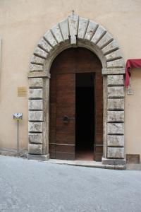 un edificio con un arco y una puerta de madera en B&B L'Agnolo Di Caroti Cinzia en Montepulciano