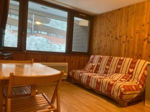 ein Wohnzimmer mit einer Couch, einem Tisch und einem Fenster in der Unterkunft Studio cosy 4 pers au cœur de Super Besse - FR-1-814-118 in Besse-et-Saint-Anastaise