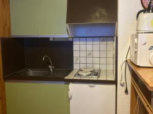 eine kleine Küche mit Spüle und Herd in der Unterkunft Studio cosy 4 pers au cœur de Super Besse - FR-1-814-118 in Besse-et-Saint-Anastaise