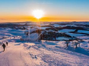 eine Gruppe von Menschen, die bei Sonnenuntergang auf einer schneebedeckten Piste Ski fahren in der Unterkunft Studio cosy 4 pers au cœur de Super Besse - FR-1-814-118 in Besse-et-Saint-Anastaise + 5 Fotos