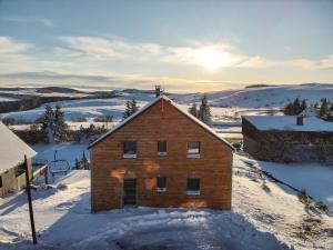 a house in the snow with the sun in the background at Chalet moderne pour 14 pers, accès PMR, parking privé - FR-1-814-121 in Besse-et-Saint-Anastaise
