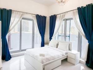 a white bed in a room with blue curtains at MK Residence JVC in Dubai