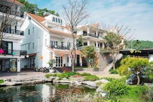 a large white house with a pond in front of it at Orestay Garden Hạ Long in Ha Long