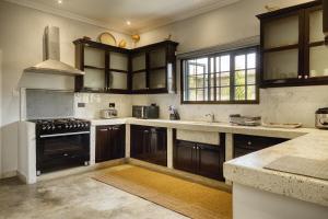 eine Küche mit Holzschränken und einem Herd mit Backofen in der Unterkunft Sarita Village Homes in Arusha