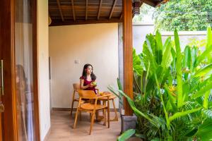 a woman sitting at a table on a porch at Cempaka Kembar Guest House Ubud in Ubud
