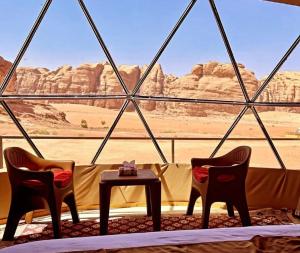 a room with two chairs and a table with a view of the desert at calm Rum in Disah