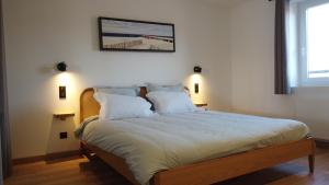 a bedroom with a large bed with white sheets and pillows at Appart Centre Village in Condette