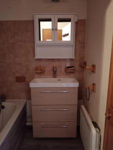 a bathroom with a sink and a mirror and a tub at Appartement confortable avec vue sur la montagne in Notre-Dame-de-Bellecombe +12 photos