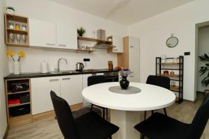a kitchen with a white table and black chairs at Fidelis Apartment - Walk to the Beach in Minutes in Novi Vinodolski
