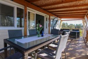 a glass table on a screened porch with chairs at Mobile Home Olive Tree in Pakoštane