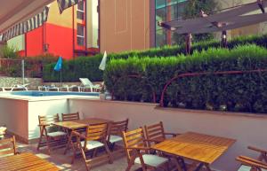 a patio with wooden tables and chairs next to a pool at Sea house Afrodita1-rooms in Nesebar