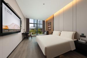 - une chambre avec un grand lit blanc et une télévision à écran plat dans l'établissement Atour Hotel Guangzhou Panyu Nancun Wanbo Subway Station, à Canton