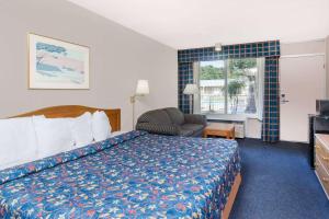 a hotel room with a bed and a chair and a window at Days Inn by Wyndham Seguin TX in Seguin