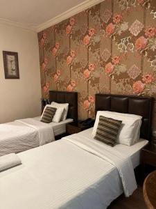 two beds in a hotel room with floral wallpaper at Aghadeer Hotel in Amman +42 photos