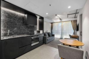メルボルンにあるClarion Apartments South Melbourneのキッチン(黒いキャビネット、テーブル、ソファ付)