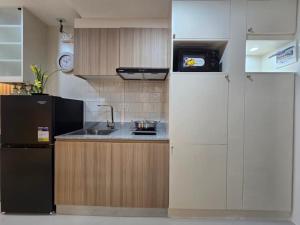 a kitchen with a sink and a black refrigerator at Studio Unit with 4 Fun Bunk Beds in Iloilo City