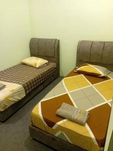 two beds sitting next to each other in a room at Tambun Lastworld Sapari Homestay in Tambun