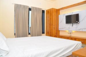 a bedroom with a white bed and a tv at Hotel Shivar in Kalam
