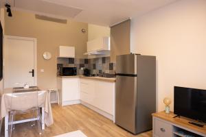 a kitchen with a stainless steel refrigerator and a table at Le Bastidon des Alpilles in Saint-Étienne-du-Grès