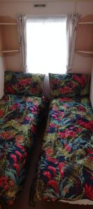 a bed in a small room with a window at 7 Headwards Caravan Retreat in Hemsby