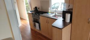 a small kitchen with a stove and a sink at 7 Headwards Caravan Retreat in Hemsby +8 photos