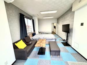 a bedroom with a bed and a couch and a table at penthouse半田 in Handa