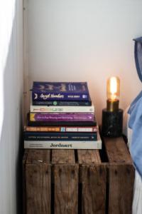 a stack of books on a wooden crate with a lamp at Cozy studio apartment in Oslo