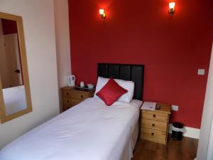 a bedroom with a bed with a red wall at River Lodge B&B Ltd in Spalding