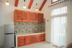a kitchen with wooden cabinets and a refrigerator at Tropangsneh Dakdam Resort in Phumĭ Pu Ântrêng (1) +34 photos