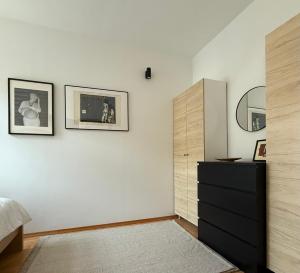 a bedroom with a black dresser and two pictures on the wall at Aumetz Square Apartment 2 in Idrija