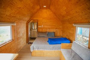 a bed in a wooden room with two windows at Tropangsneh Dakdam Resort in Phumĭ Pu Ântrêng (1)