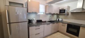 Una cocina con gabinetes blancos y un refrigerador de acero inoxidable. en Mangue-carotte, en Saint-Denis 2 fotos más