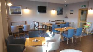 a restaurant with wooden tables and blue chairs at Park Hotel in Thurso