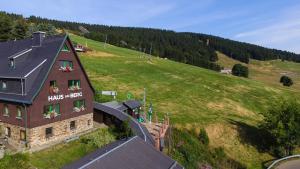 ein Gebäude mit Blumen in den Fenstern auf einem Hügel in der Unterkunft Haus am Berg - Pension direkt am Skihang in Kurort Oberwiesenthal