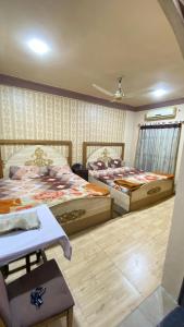 a bedroom with two beds and a table in it at Citi Hotel & Community Club in Faisalabad