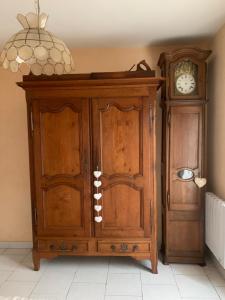 un meuble en bois avec une horloge à côté d'un mur dans l'établissement Havre de Paix, à Villeneuve-sur-Lot