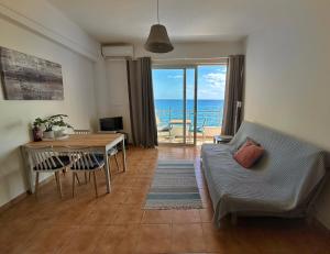 a living room with a couch and a table with a view of the ocean at Pelagos Apartments in Myrtos