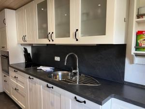 a kitchen with white cabinets and a sink at Apartment BERGfamilie - gemütlich ausgestattet, ruhig und familienfreundlich in Schliersee +5 photos