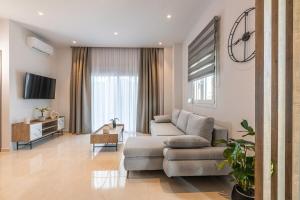 een woonkamer met een bank en een tv bij Lume, Stylish New Apartment Near the Beach in Agia Pelagia