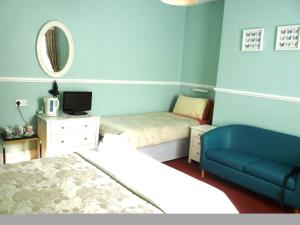 a bedroom with a bed and a couch and a mirror at The Norman Guest House in Dover