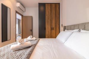 een slaapkamer met een groot wit bed met handdoeken erop bij Lume, Stylish New Apartment Near the Beach in Agia Pelagia