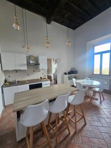 a kitchen with a wooden table and white chairs at Suites Palazzo Ianni in Vallerano