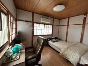 a bedroom with a bed and a desk with a chair at ムラキン民泊 in Higashi-osaka