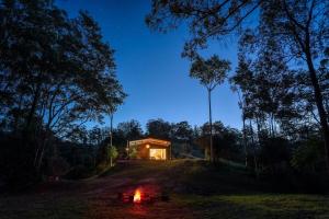 a house on a hill with a fire in front of it at Off-Grid Eco Cabin in Bellingen